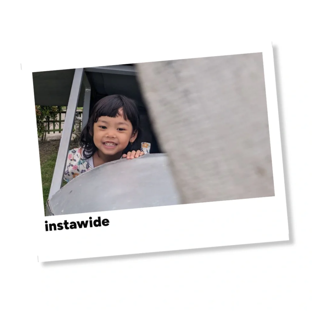 Anak perempuan tersenyum ceria di balik struktur logam dalam bingkai polaroid instawide yang estetik.